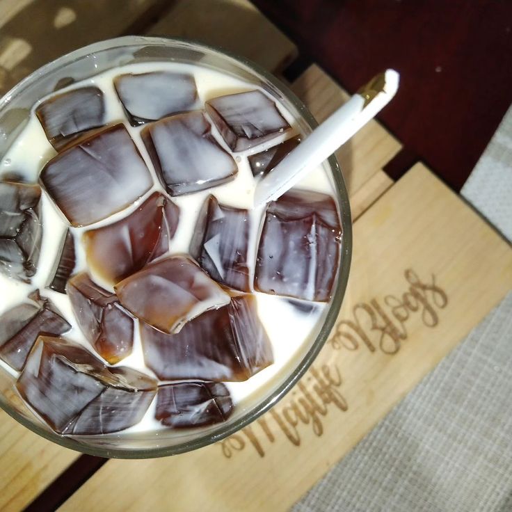 a glass filled with ice and chocolate on top of a wooden table