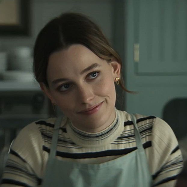 a woman in an apron is looking at the camera with blue eyes and brown hair