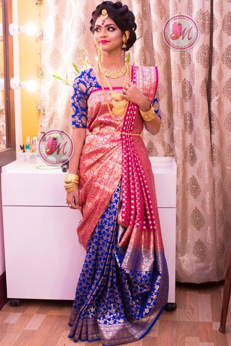 a woman in a blue and pink sari standing next to a dresser with a mirror