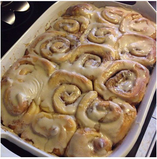 a pan filled with cinnamon rolls sitting on top of a stove