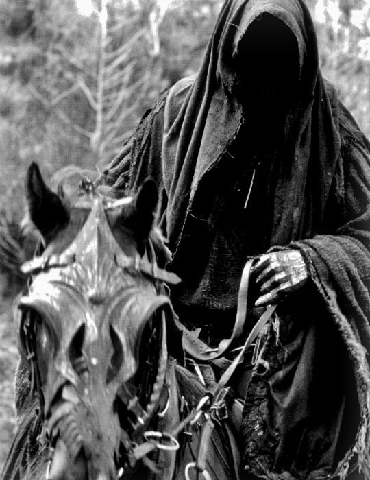 a black and white photo of a person riding a horse with a mask on it's face