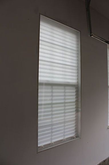 three windows with white blinds in an empty room, one is closed and the other has no curtains