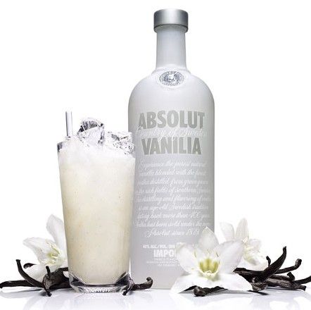 a bottle of absolut vanilla next to a glass filled with ice and flowers