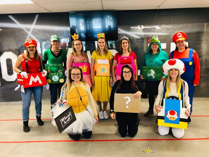 a group of people dressed in costumes posing for a photo with one person holding a cardboard sign