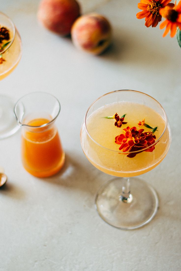 two glasses filled with orange juice and garnished with flowers on the rims