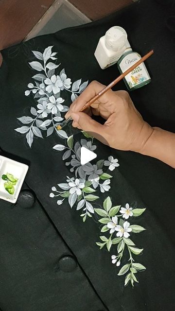 someone is painting flowers on a black shirt