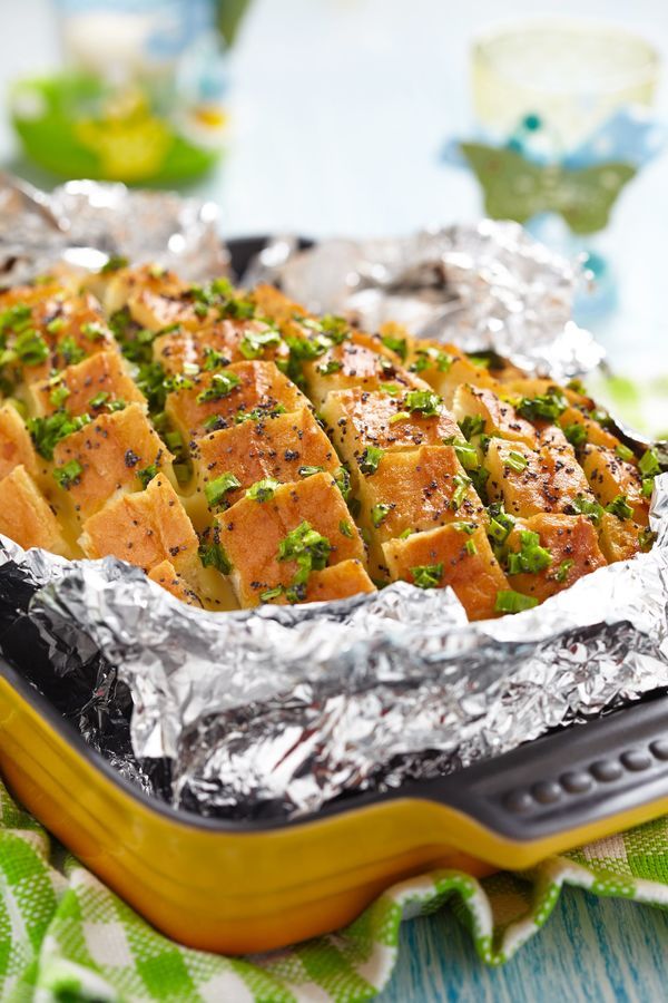 a pan filled with food sitting on top of a green and white table cloth covered in tin foil