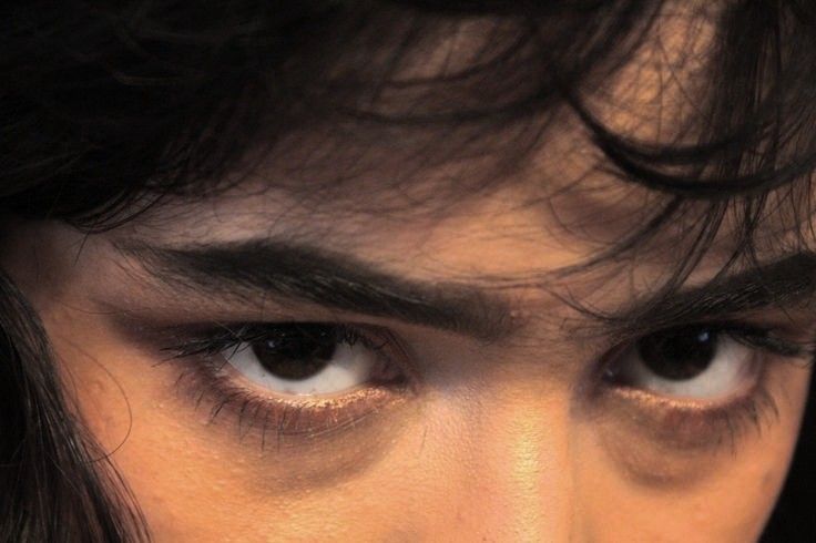 a close up of a person's face with long black hair and white eyes