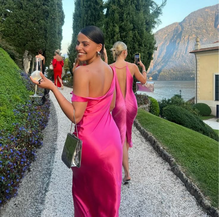 two women in pink dresses walking down a path