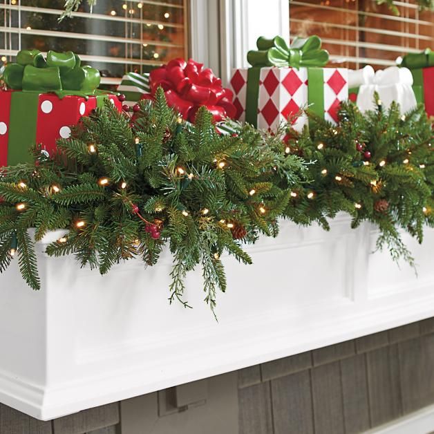 christmas decorations on the mantle in front of a window with presents wrapped in red and green