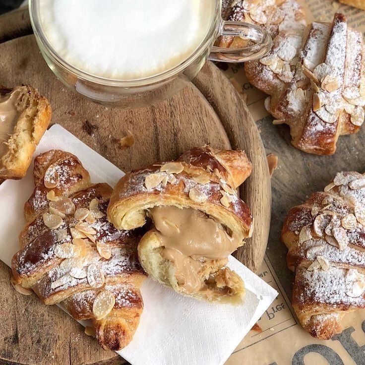 pastries with peanut butter and powdered sugar sit on a wooden tray next to a glass of milk