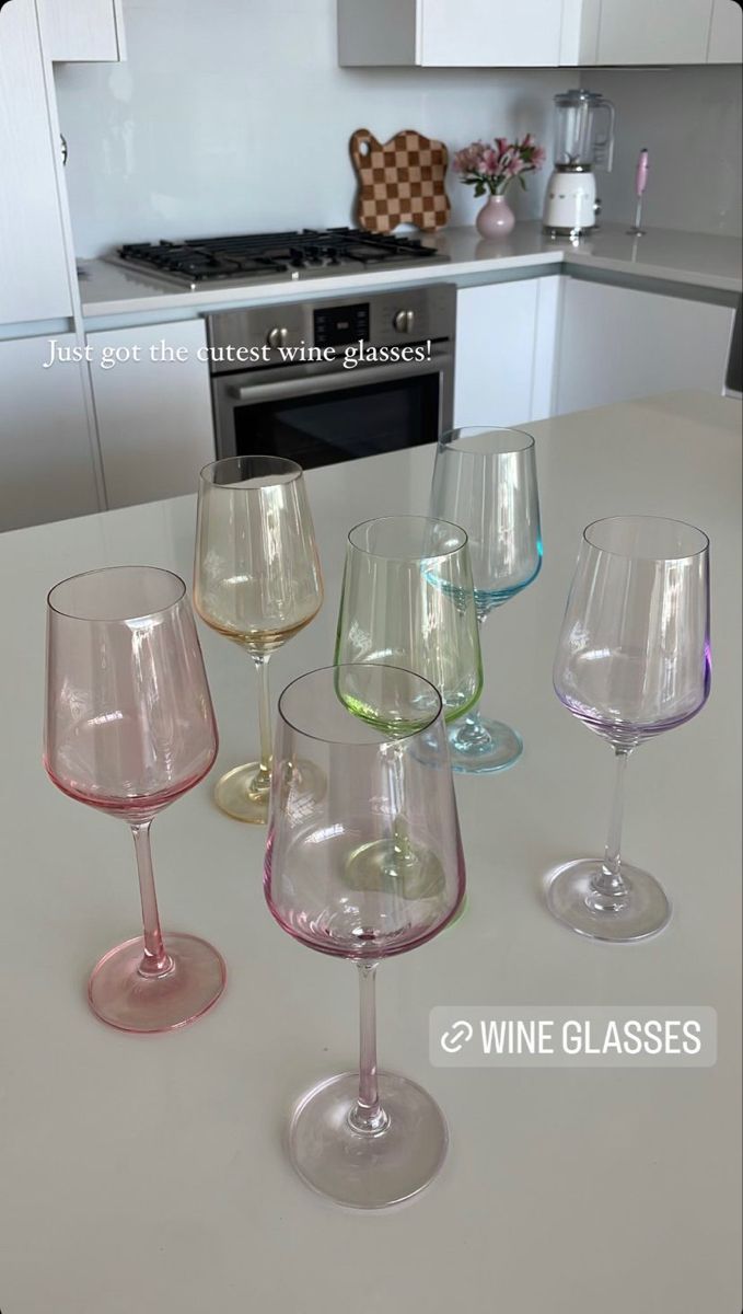 four wine glasses sitting on top of a counter next to an oven and stovetop