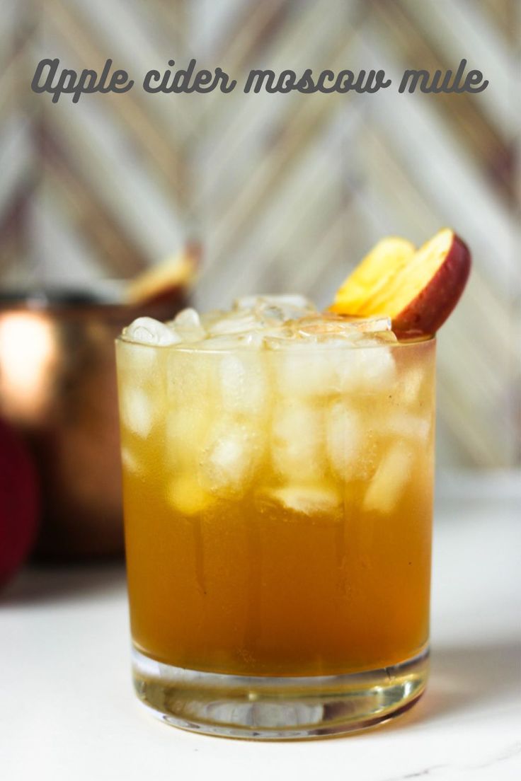 an apple cider masquer mule is garnished with sliced apples and ice