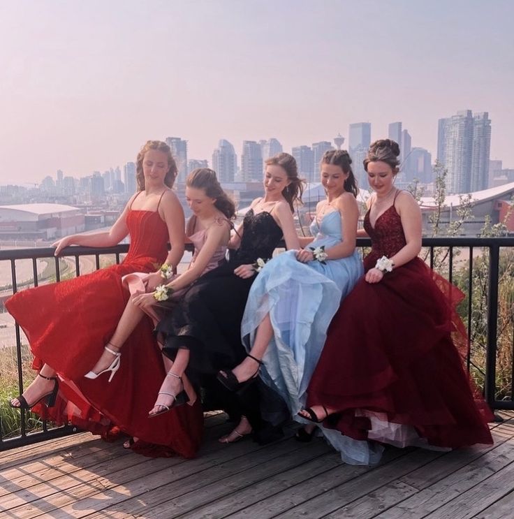 four women in dresses are sitting on a balcony