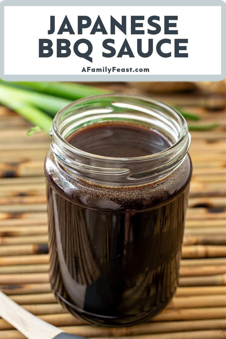 a jar filled with brown liquid sitting on top of a bamboo mat next to a spatula