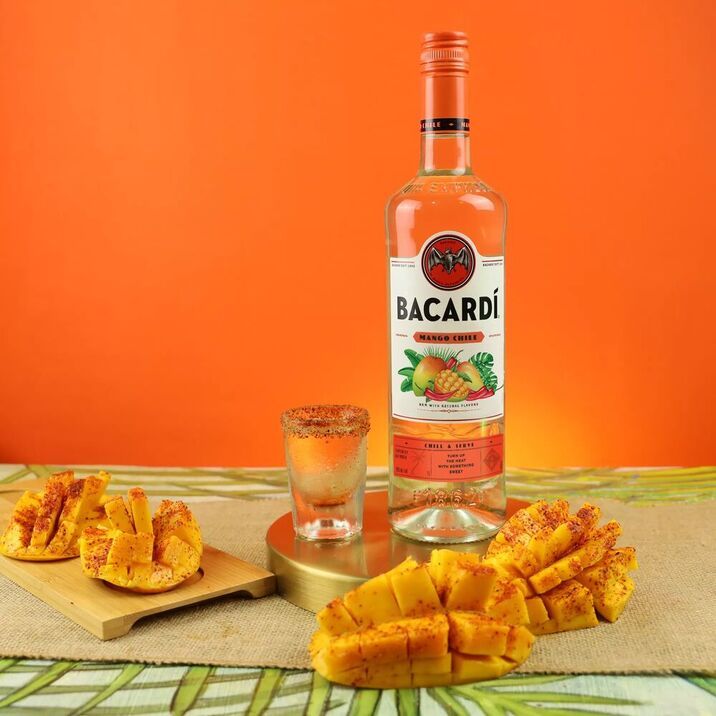 a bottle of bacardi rum next to sliced pineapples on a table