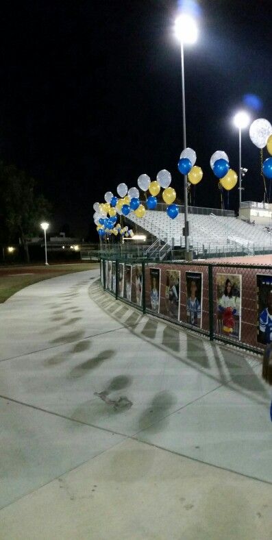 there are many balloons in the air at this baseball game, as well as pictures on the fence