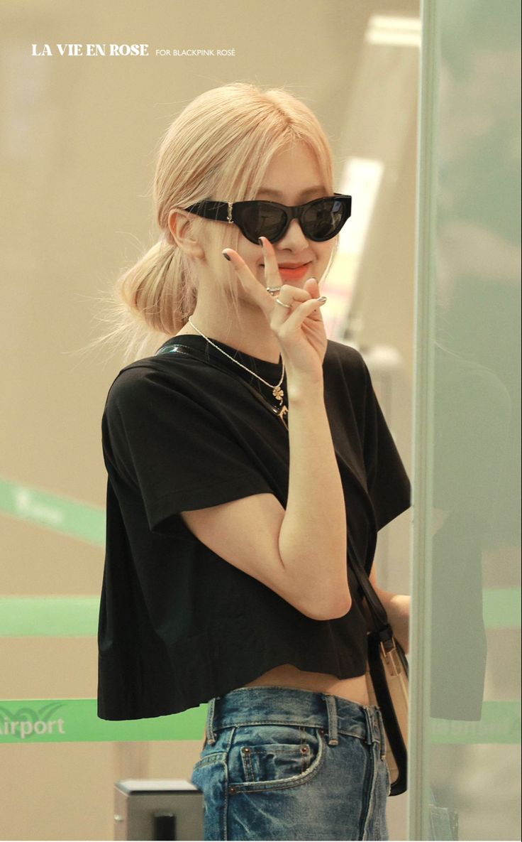 a woman in black shirt and sunglasses talking on cellphone with her hand to her mouth