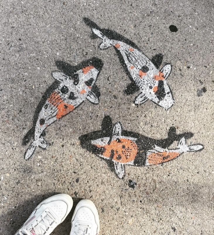 three fish painted on the ground next to white shoes and a person's feet