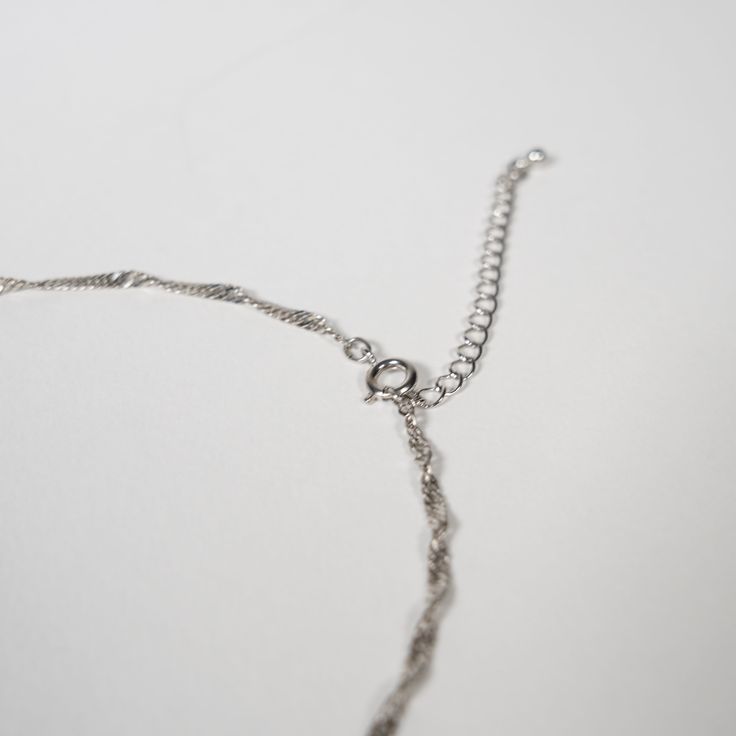 a close up of a silver chain on a white surface