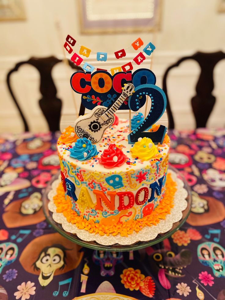 a colorful birthday cake sitting on top of a table next to a plate with a guitar