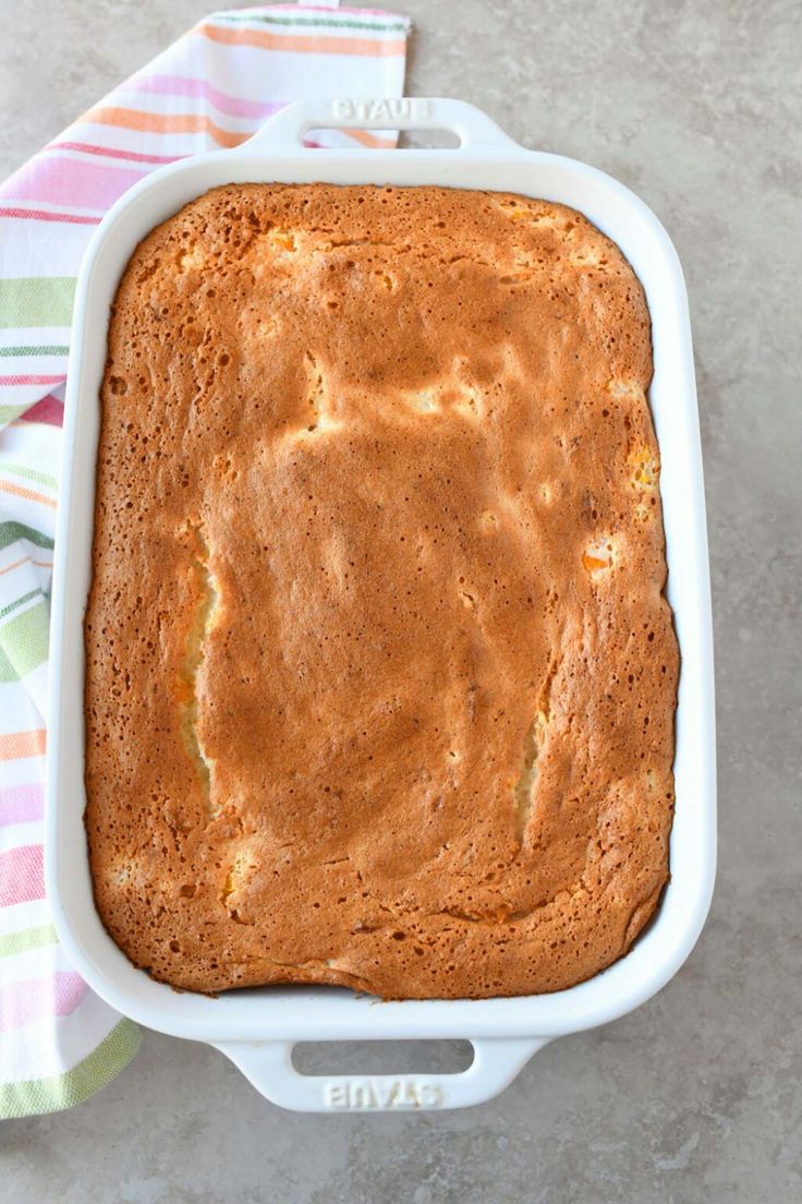 a baked cake in a white dish on a colorful towel