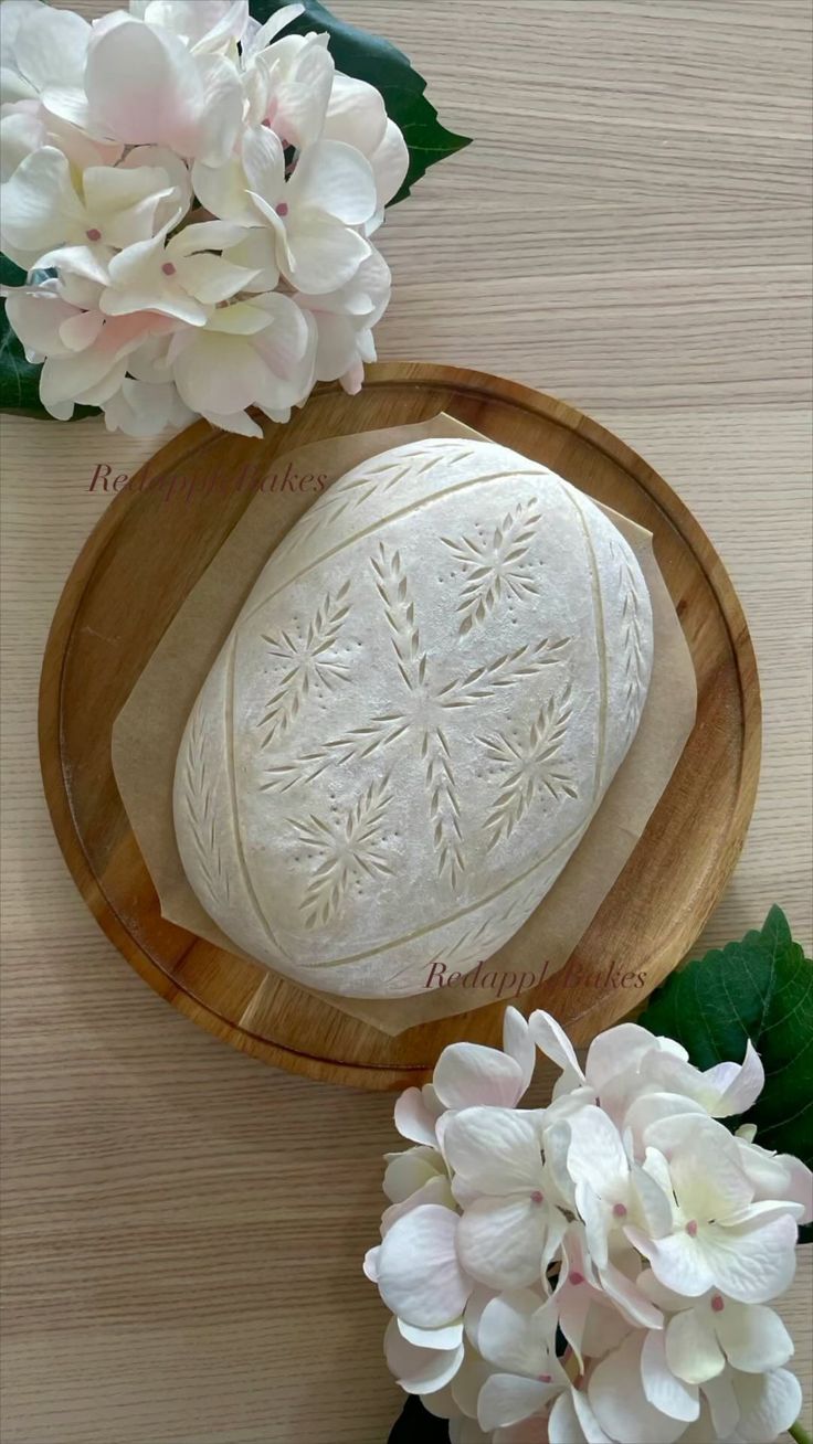 a wooden bowl filled with white bread next to flowers on top of a wood table