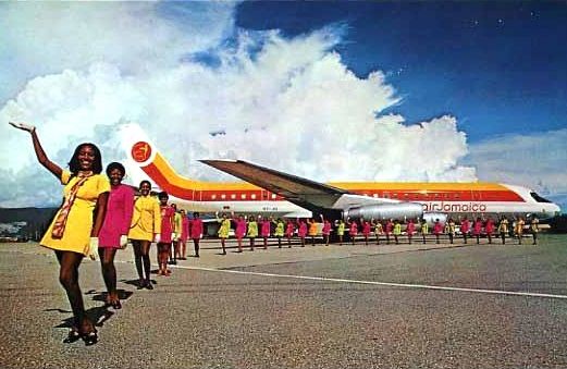 a group of women standing in front of an orange and white plane on the tarmac