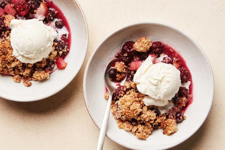 two white bowls filled with fruit and ice cream on top of a beige countertop