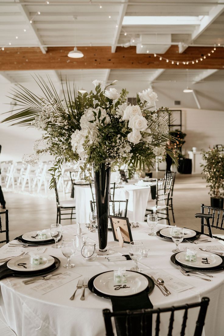 a table is set with white flowers and place settings for an elegant dinner party or reception