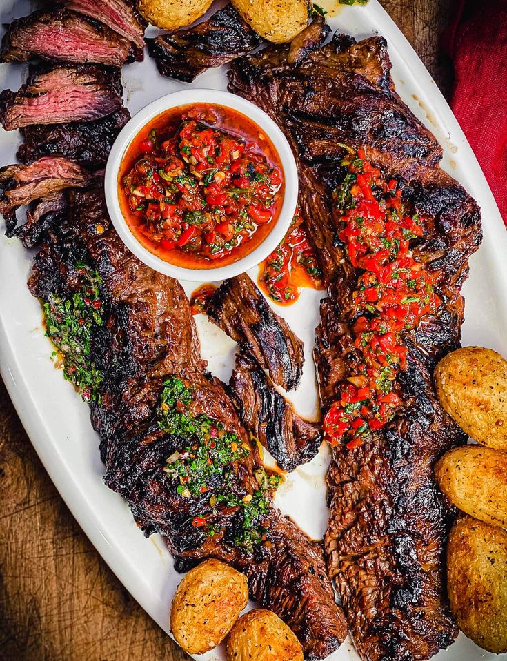 a platter with steak, potatoes and salsa on it is ready to be eaten