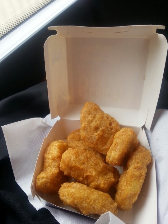 chicken nuggets are in a box on a table next to some napkins