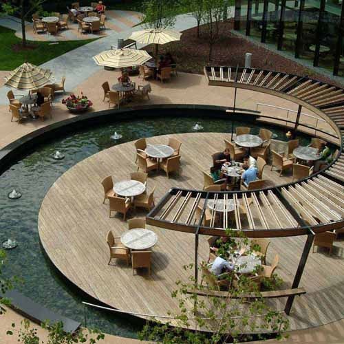 an outdoor dining area with tables and umbrellas on the deck next to a pond