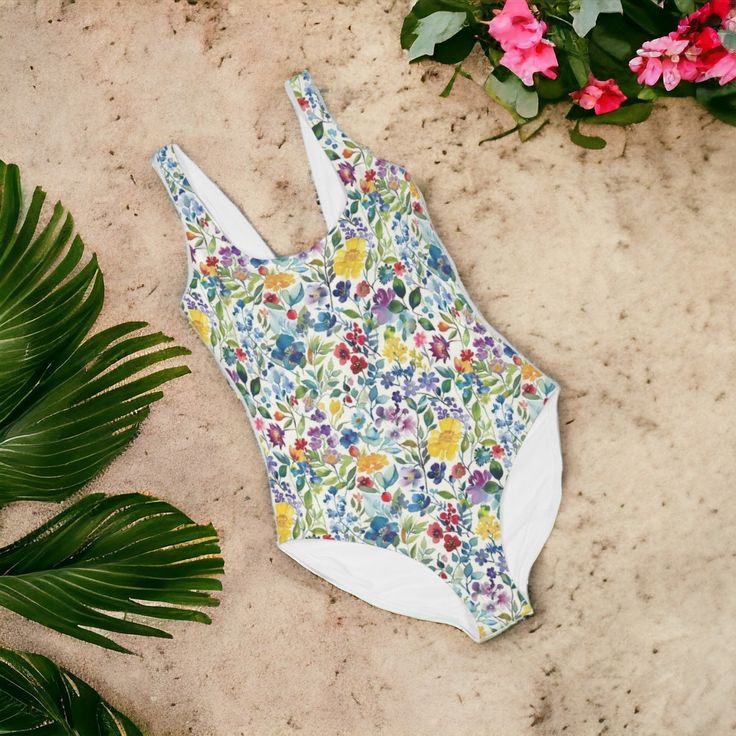 Wrap yourself in the splendor of our Blossom Elegance One-Piece Swimsuit, a perfect blend of style, comfort, and responsible fashion. Adorned with a vibrant, blooming floral pattern, this eco-friendly swimsuit will become your go-to piece for every splashy occasion. Crafted with a stretchy blend of 80% Polyester and 20% Spandex, this suit promises a snug yet comfortable fit that adapts to your movements. The scoop neck and tank straps outline an elegant silhouette, offering modest coverage without sacrificing allure. The built-in bra with soft removable cups provides the support you desire, making it ideal for diverse body types. Whether lounging poolside or riding waves, the UPF 50+ fabric ensures you're shielded from the sun's rays. Handmade with an eye for quality, this one-piece boasts Fitted Uv Protection Swimwear For Spring, Spring Beachwear Swimwear For Water Sports, Casual Fitted Swimwear With Uv Protection, Summer Swimwear For Beach Season Water Sports, Summer Swimwear For Water Sports And Beach Season, Tropical Fitted Swimwear For Sunbathing, Tropical Swimwear For Sunbathing, Summer Stretch Swimwear For Water Sports, Casual Fitted Swimwear With Upf 50+