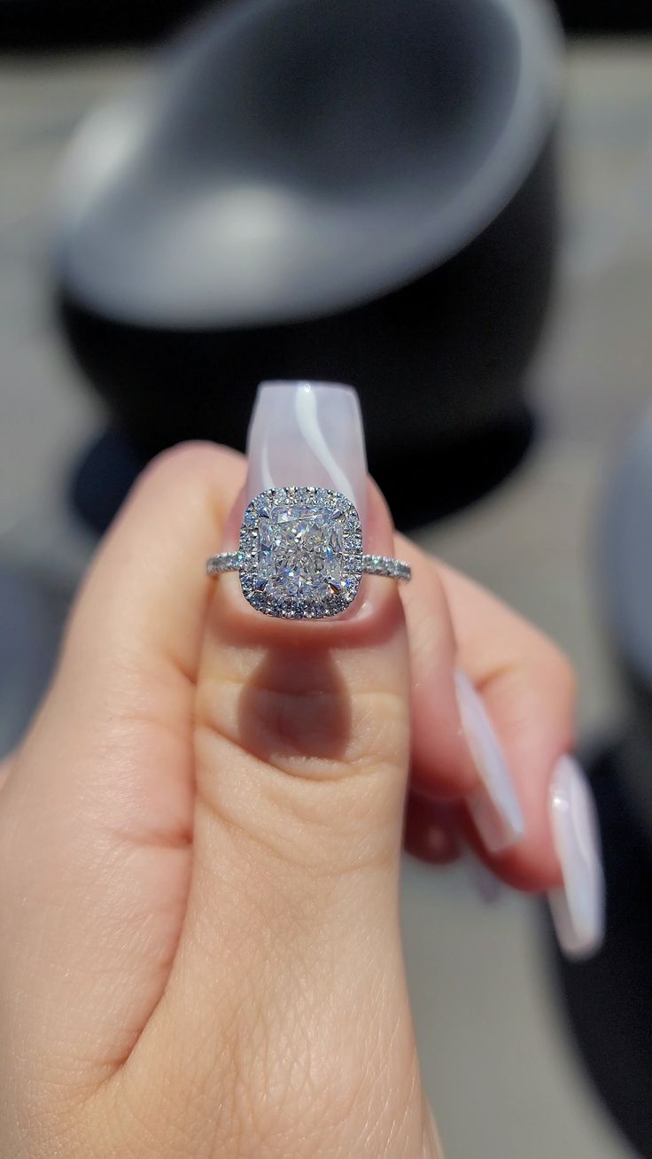 a woman's hand holding an engagement ring with a diamond in the middle and on top of it