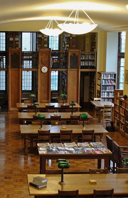 an empty library filled with lots of wooden tables and chairs next to bookshelves