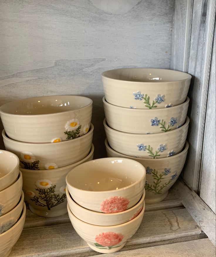 a bunch of bowls that are stacked on top of each other with flowers painted on them