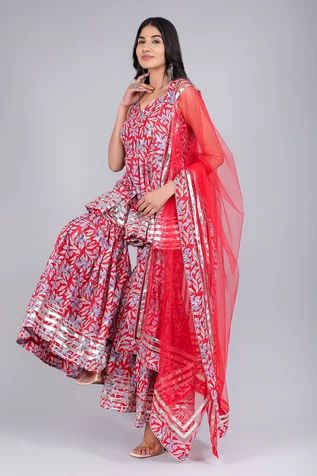 Red sleeveless printed anarkali with metallic stripes and sweetheart neckline. Paired with sharara and printed hem dupatta.
Component: 3
Pattern: Printed
Type Of Work: Floral
Neckline: Sweetheart
Sleeve Type: Sleeveless
Fabric: Anarkali and Sharara: Cotton, Dupatta: Soft Net
Color: Red
Other Details: 
Printed hem dupatta
Metalic stripes
Occasion: Wedding - Aza Fashions Red Anarkali Style Sharara For Festive Season, Red Anarkali Sharara For Festive Occasions, Festive Red Anarkali Style Sharara, Anarkali Chandbali Red Sets, Red Georgette Sharara With Cutdana, Anarkali Red Sharara With Pallu, Red Sharara With Cutdana For Navratri, Transitional Red Anarkali Set With Mirror Work, Fitted Red Palazzo Set With Sheer Dupatta