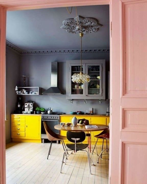 an open door leading to a kitchen with yellow cabinets and black dining room chairs in it