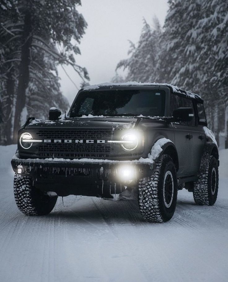 a truck driving down a snowy road with headlights on it's headlamps