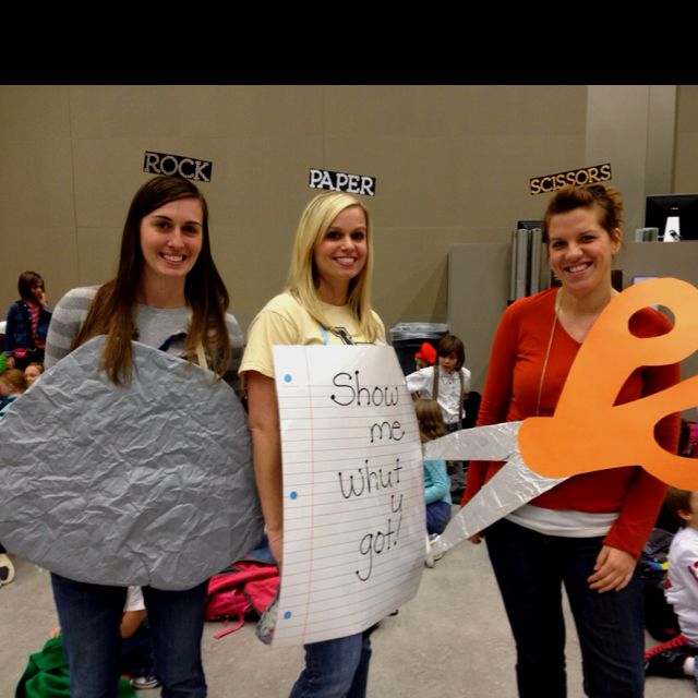 three girls are holding paper and scissors in front of them