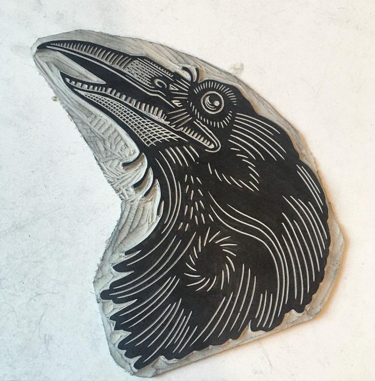 a black and white drawing of a bird on a rock ornament in the shape of a raven