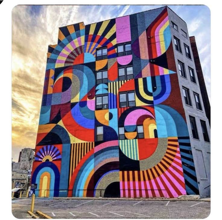 a large colorful mural on the side of a tall building in front of a cloudy sky