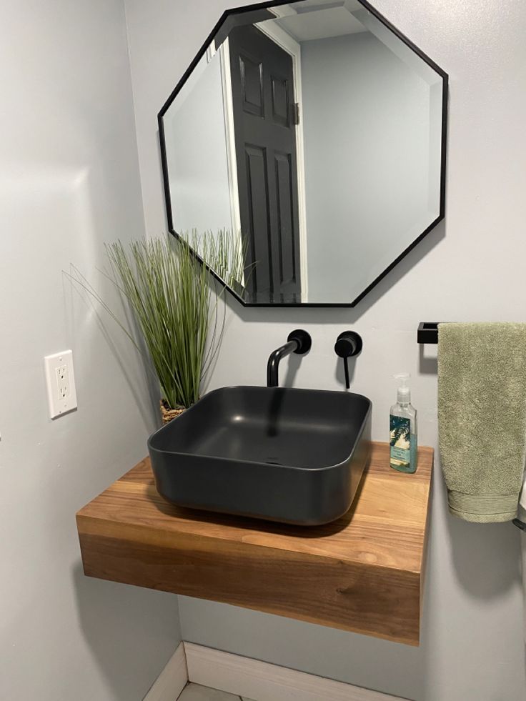 a bathroom sink sitting under a mirror next to a towel rack and potted plant