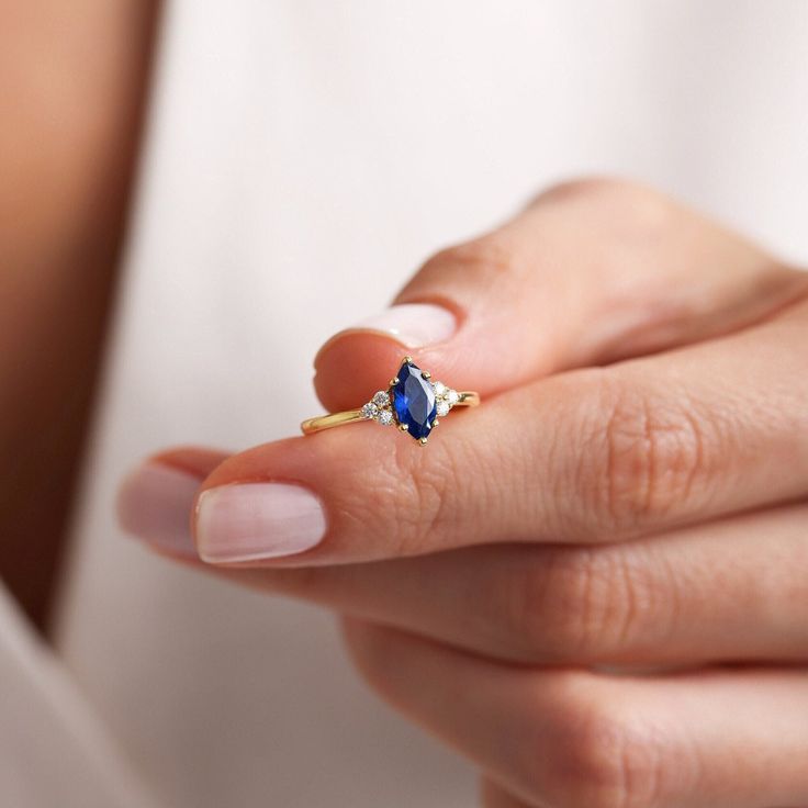 a woman's hand holding a ring with a blue stone