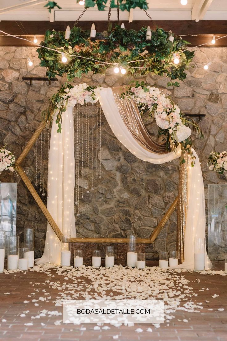 a wedding ceremony with candles and flowers on the floor in front of a stone wall