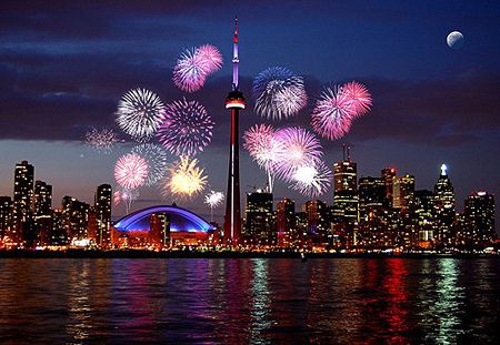 fireworks are lit up in the night sky over a cityscape and lake ontario