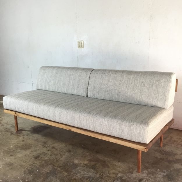 a white couch sitting on top of a wooden frame in a living room next to a wall