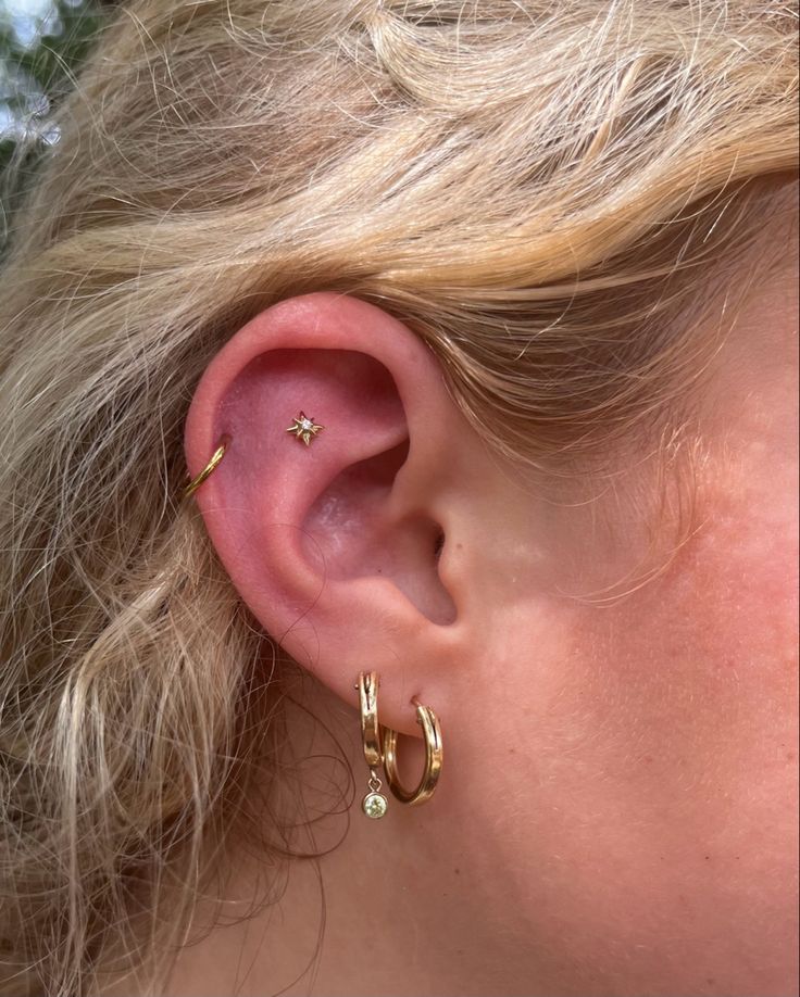 a close up of a person's ear with two small gold hoops on it