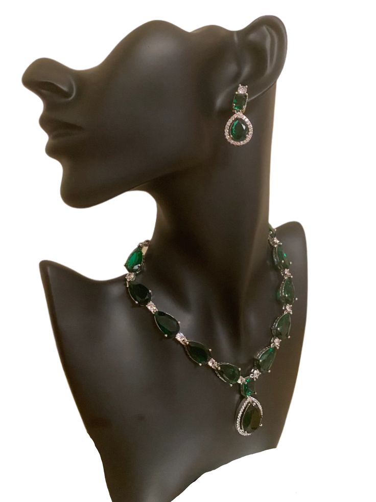 Experience the beauty and elegance of our CZ American Diamond Necklace. Adorned with stunning green stones, this necklace is perfect for any occasion, whether it's a wedding, party, or a gift for someone special. Pair it with outfits like sarees, gowns, or lehengas to complete your look. This jewellery set includes a necklace and matching earrings. Jewellery Care- Keep the jewellery dry, avoid contact with perfumes and water. Dazzling Green Emerald Necklace, Elegant Kundan Emerald Necklace For Festive Occasions, Elegant Emerald Kundan Necklace For Festive Occasions, Green Cubic Zirconia Jewelry For Evening, Evening Green Cubic Zirconia Jewelry, Green Emerald Bridal Necklace Gift, Elegant Emerald Kundan Necklace For Gift, Elegant Green Kundan Necklace For Festive Occasions, Dazzling Green Emerald Necklace For Formal Occasions